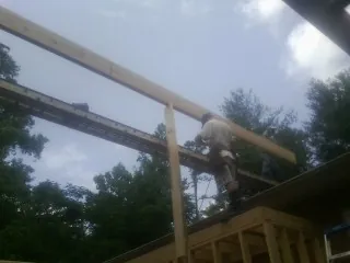 Carpenter setting a ridge beam over a new addition frame — Ice Dam Removal by Roofing Brothers in Bottineau