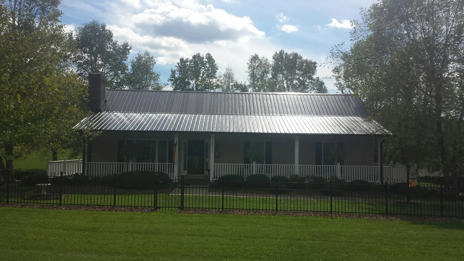 Gray metal roof on a brick ranch with a full width front porch — Gutter Guard Installation work by our crew in Bottineau