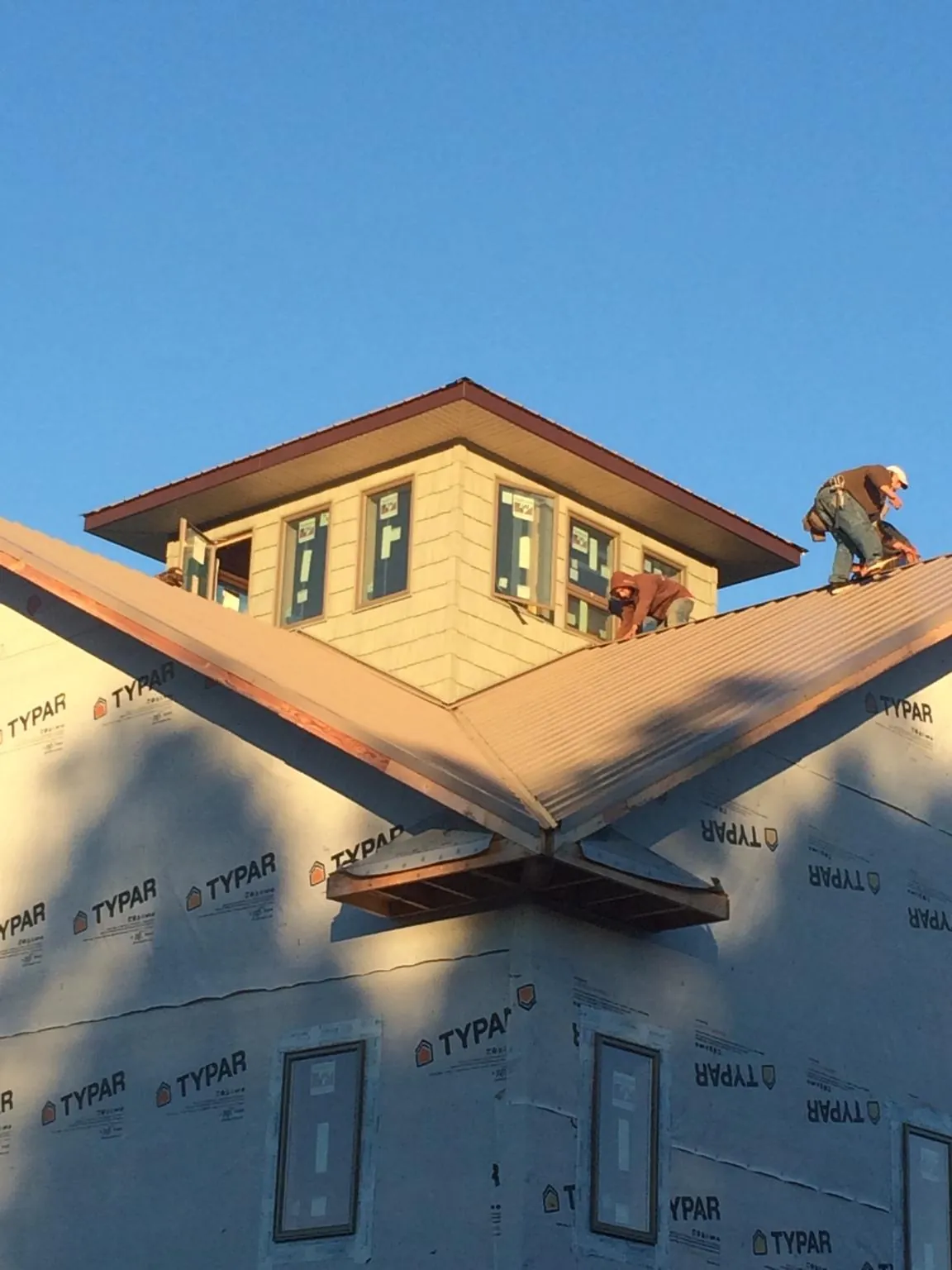 Roofers working around a rooftop cupola on a new metal roof at sunset — Roof Waterproofing in Bottineau by Roofing Brothers